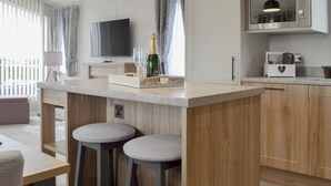 A modern kitchen with wooden cabinets, a built-in microwave, and a bar area with stools. - 2 bedroom accommodation in Calthwaite, near Penrith (Calthwaite, near Penrith)