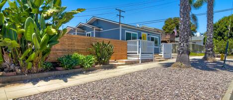 A residential property with a wooden fence, a gravel driveway, and a house with a white exterior.