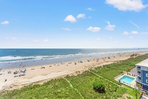 Une vue sur la plage, avec une piscine et un bâtiment doté d’un balcon.