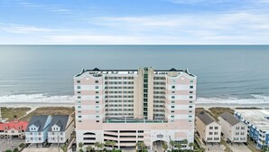 A multi-story hotel with a central atrium, located near a beach with ocean views.