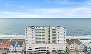Un hôtel à plusieurs étages doté d’un atrium central, situé près d’une plage offrant une vue sur l’océan.