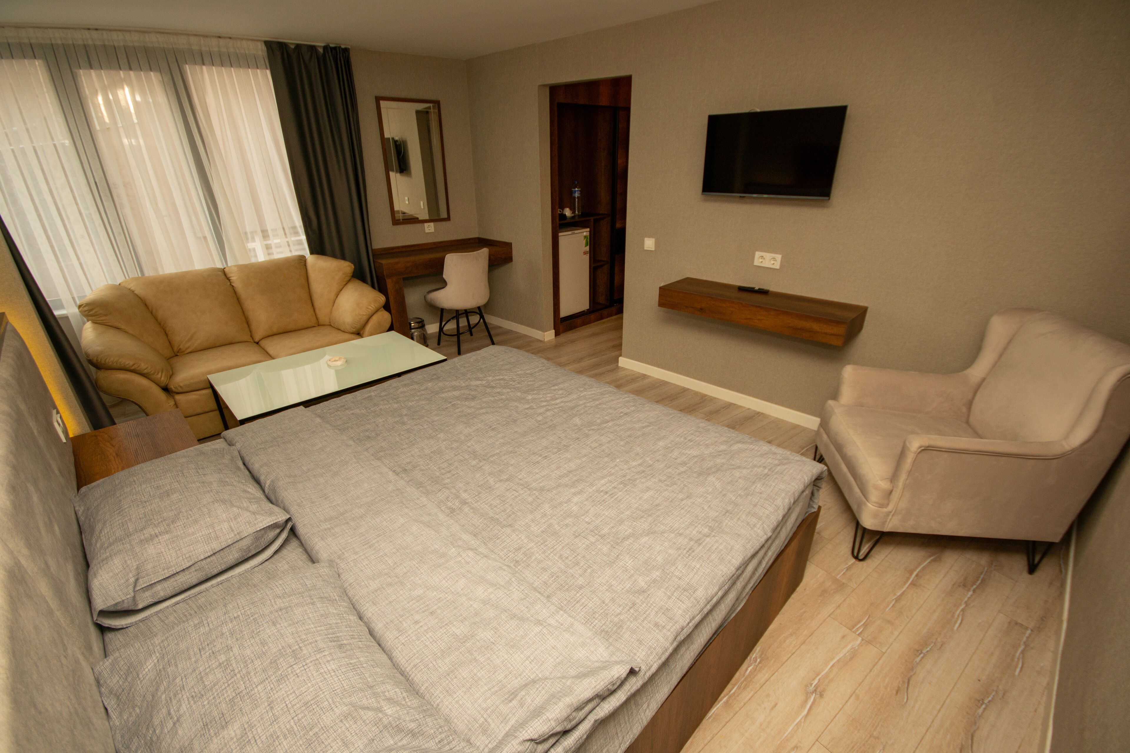 Una habitación de hotel con cama, escritorio, silla, televisor y armario.