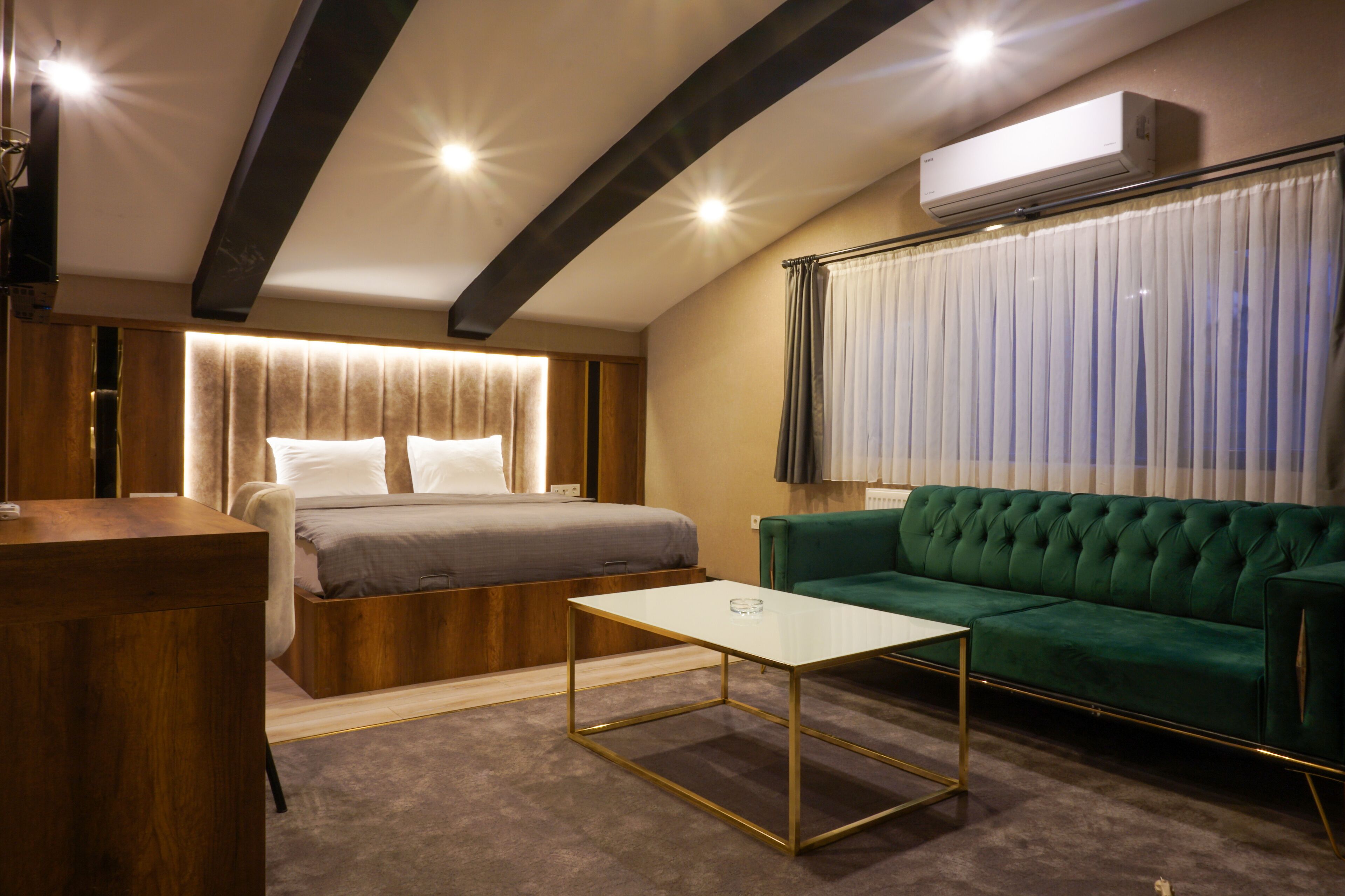 A modern bedroom with a bed, a green sofa, and a small white table.