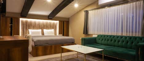 Un dormitorio moderno con una cama, un sofá verde y una pequeña mesa blanca.