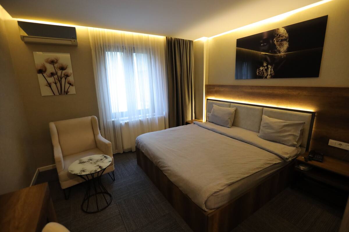 Une chambre d’hôtel avec un lit, une chaise, une petite table et un tableau au mur.