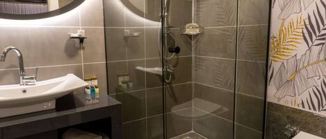 Un baño moderno con ducha de vidrio, lavamanos blanco y retrete.