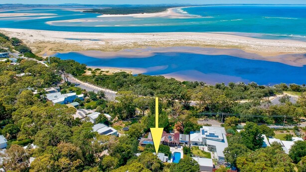 An aerial view of a coastal area with a large body of water, sandy beaches, and a residential area with houses and greenery. - Sunset Beach Shack on Surf (Inverloch)