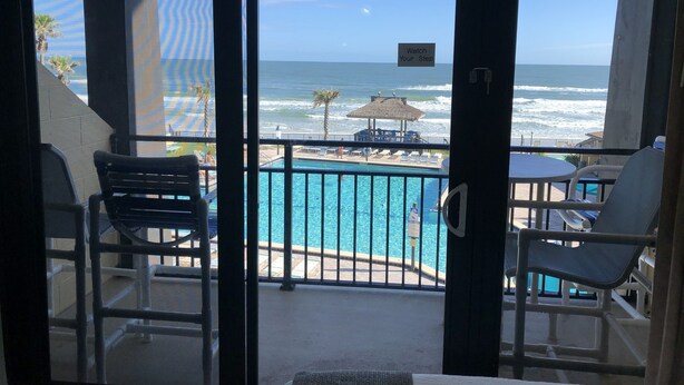 Ein Balkon mit Blick auf einen Pool und den Ozean.