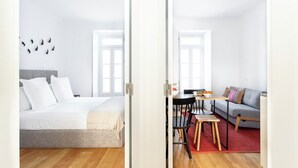 A modern hotel room with a bed, a small dining area, and a sofa. - FLH Vila Rosário Cosy Flat II (Lisbon)