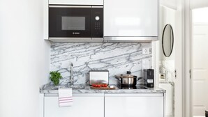 A modern kitchen with a Bosch microwave, a toaster, and a coffee maker on a marble countertop. - FLH Vila Rosário Cosy Flat II (Lisbon)