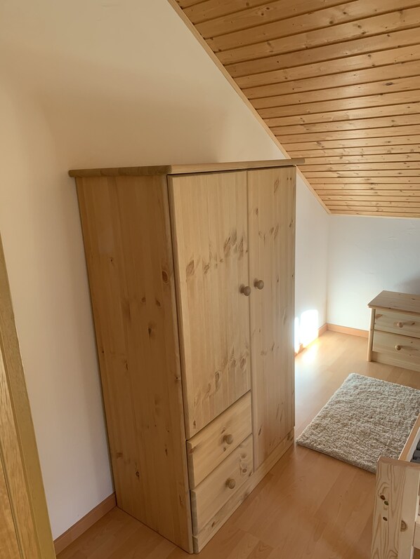 Ein Zimmer mit einem Holzschrank, einem Holzkommode und einer Holzbalkendecke.