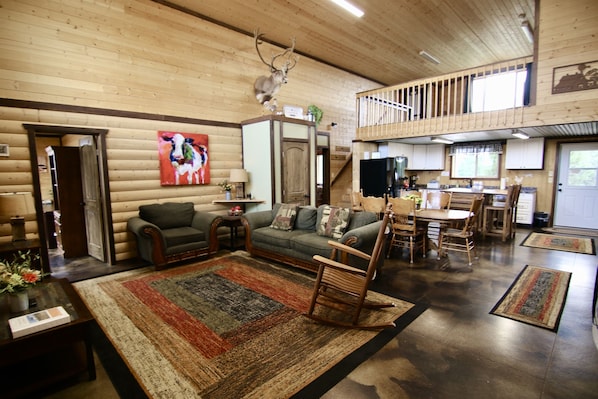 A log cabin interior with a living room, dining area, and kitchen.