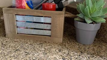 A wooden crate with tools and a potted succulent on a granite countertop.