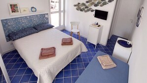 A bedroom with a bed, a desk, a chair, a TV, and a ceiling fan. - AB_Apartment  (Marina di Ragusa)