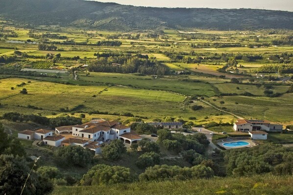 A rural landscape with a cluster of white buildings, a swimming pool, and surrounding fields. - Tenuta Su Vrau (Torpe)