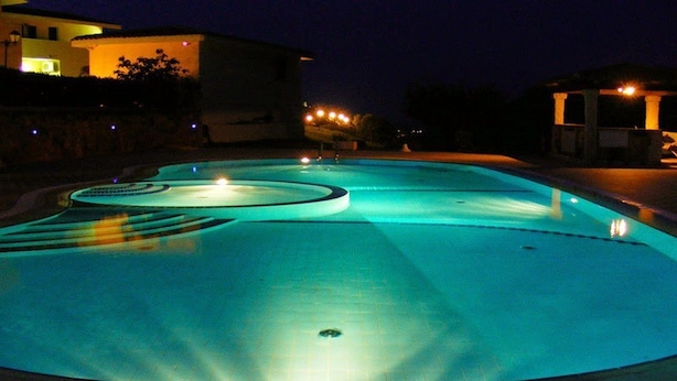 A swimming pool at night with illuminated edges and a central drain.