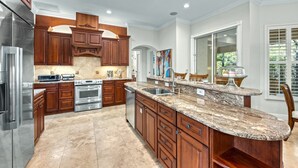 A spacious kitchen with wooden cabinets, stainless steel appliances, and a granite countertop.