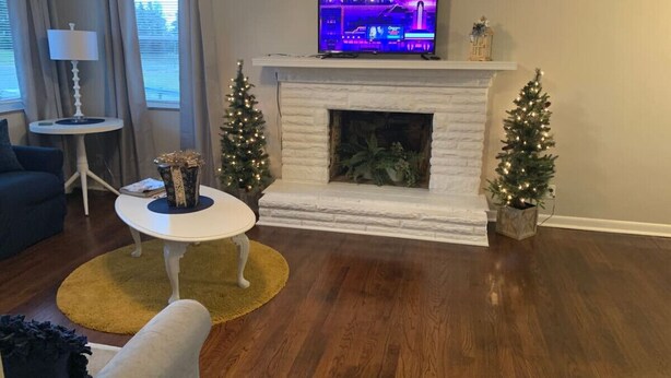 Una sala de estar con chimenea, televisor, dos árboles de Navidad y una mesa de centro.