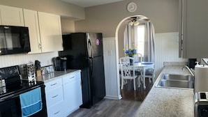 Una cocina compacta con microondas, estufa, refrigerador y un comedor con mesa y sillas.
