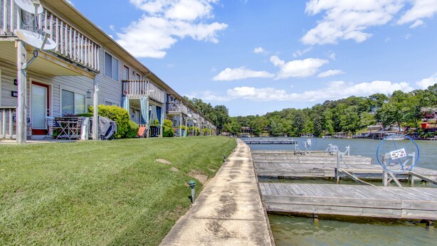 A row of waterfront cabins with a grassy lawn and dock extending into the water. - Lake Front Condo with Boat Slip / Unit 9 / Close to Bathhouse Row and Oaklawn! (Hot Springs)