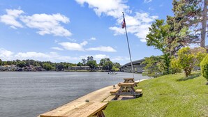 A riverside picnic area with wooden benches and a flagpole. - Lake Front Condo with Boat Slip / Unit 9 / Close to Bathhouse Row and Oaklawn! (Hot Springs)