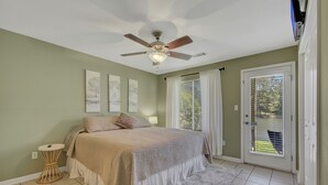 A bedroom with a bed, ceiling fan, artwork on the wall, and a view through the door. - Lake Front Condo with Boat Slip / Unit 9 / Close to Bathhouse Row and Oaklawn! (Hot Springs)