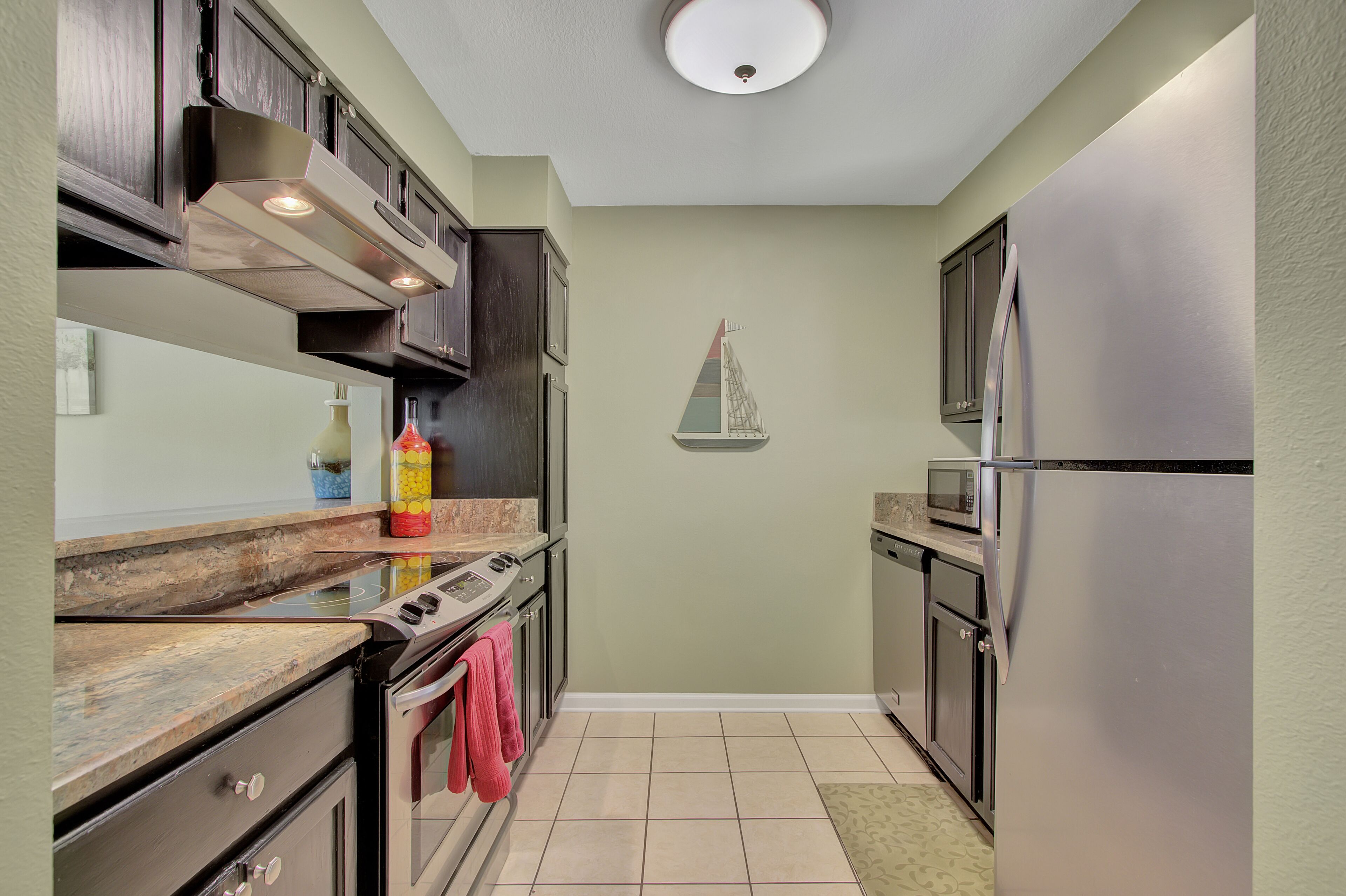 A compact kitchen with dark cabinetry, a stainless steel refrigerator, a microwave, and a stove.