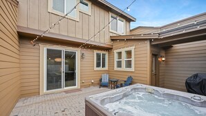 En trädgård med en bubbelpool, ljusslingor och utemöbler.