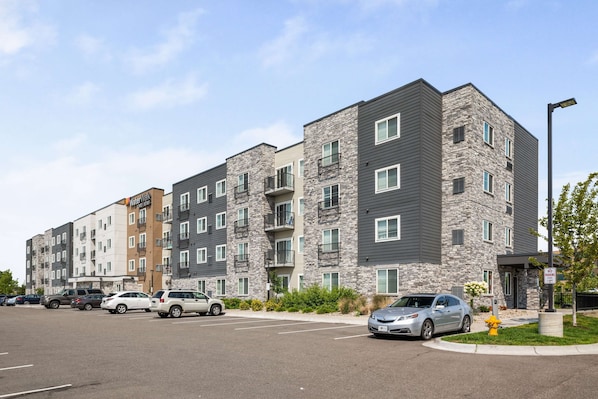 A multi-story apartment building with a parking lot in front.