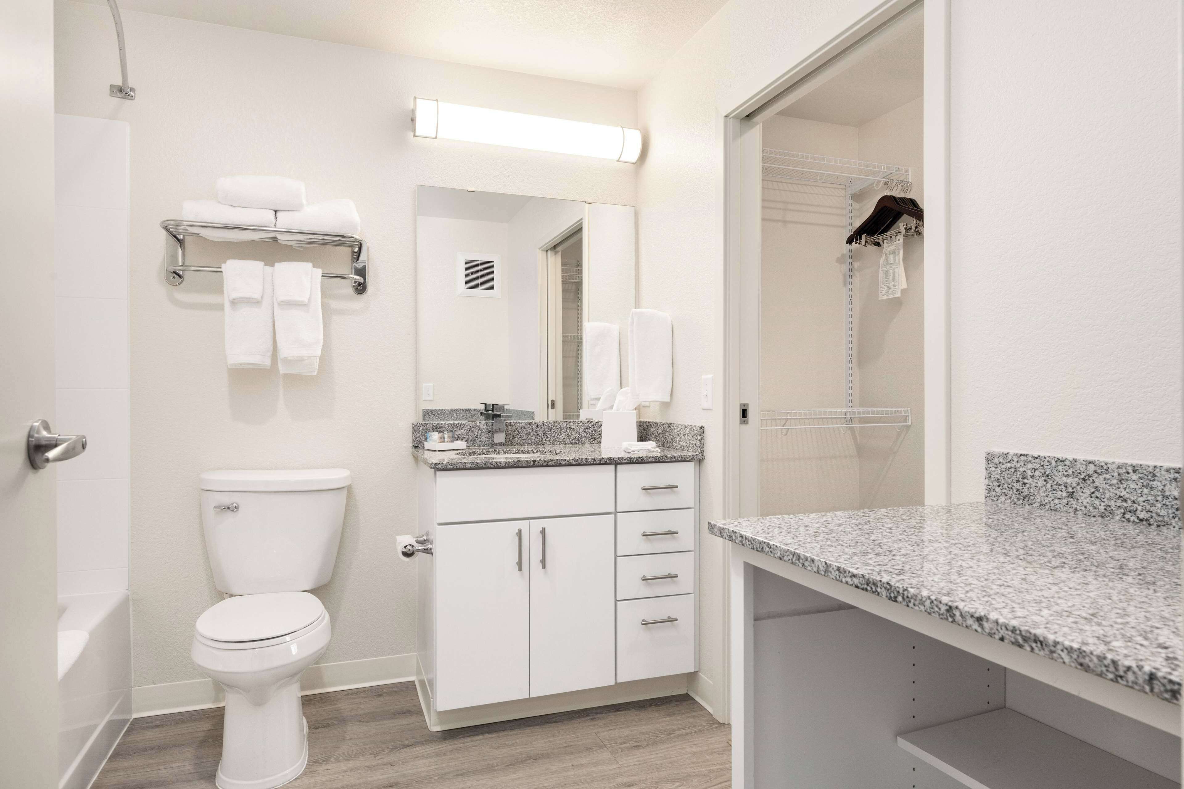 Ein modernes Badezimmer mit Toilette, Waschtisch mit Spiegel und Handtuchhalter.