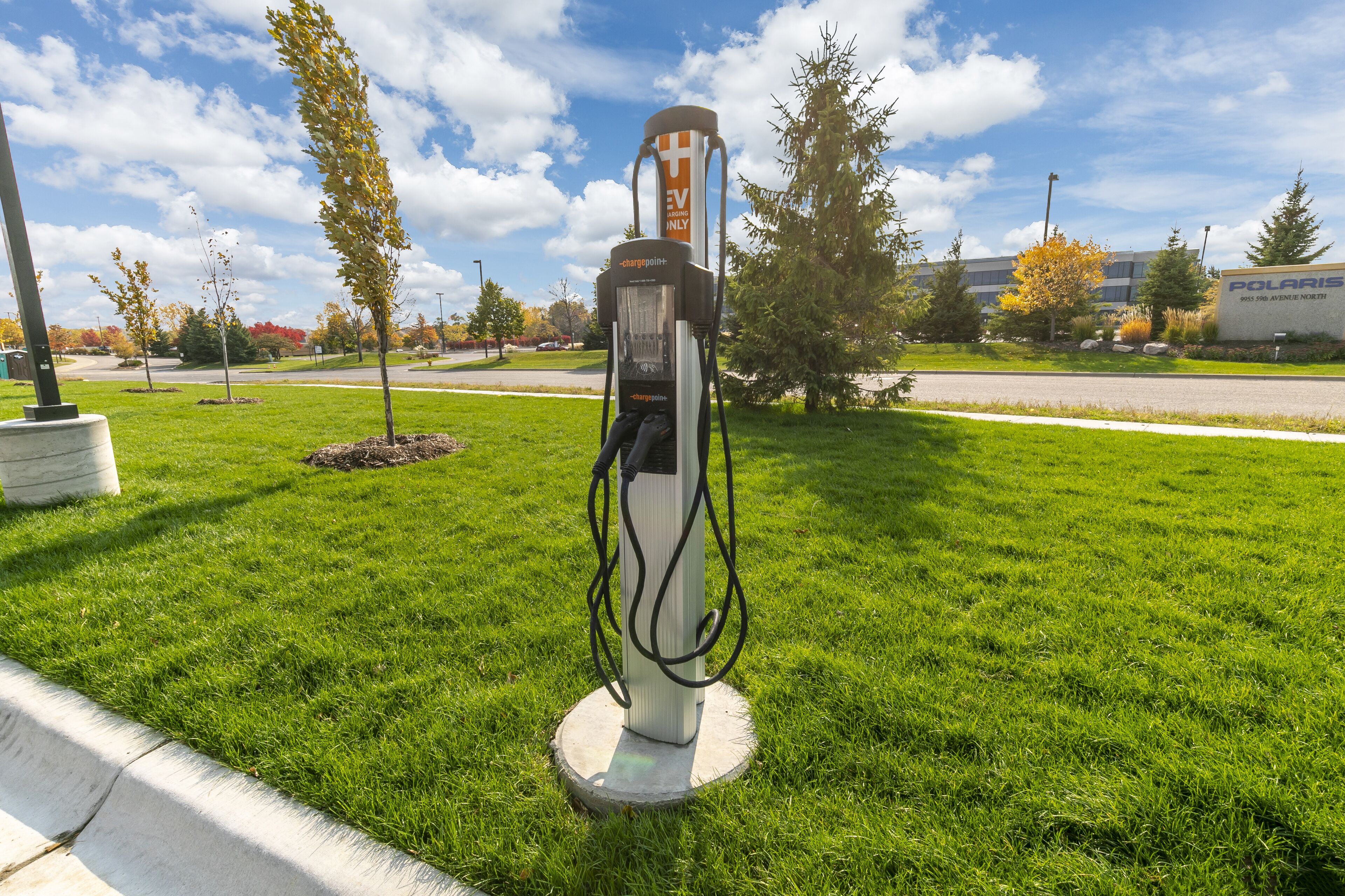 A charging station in a grassy area with a building in the background.