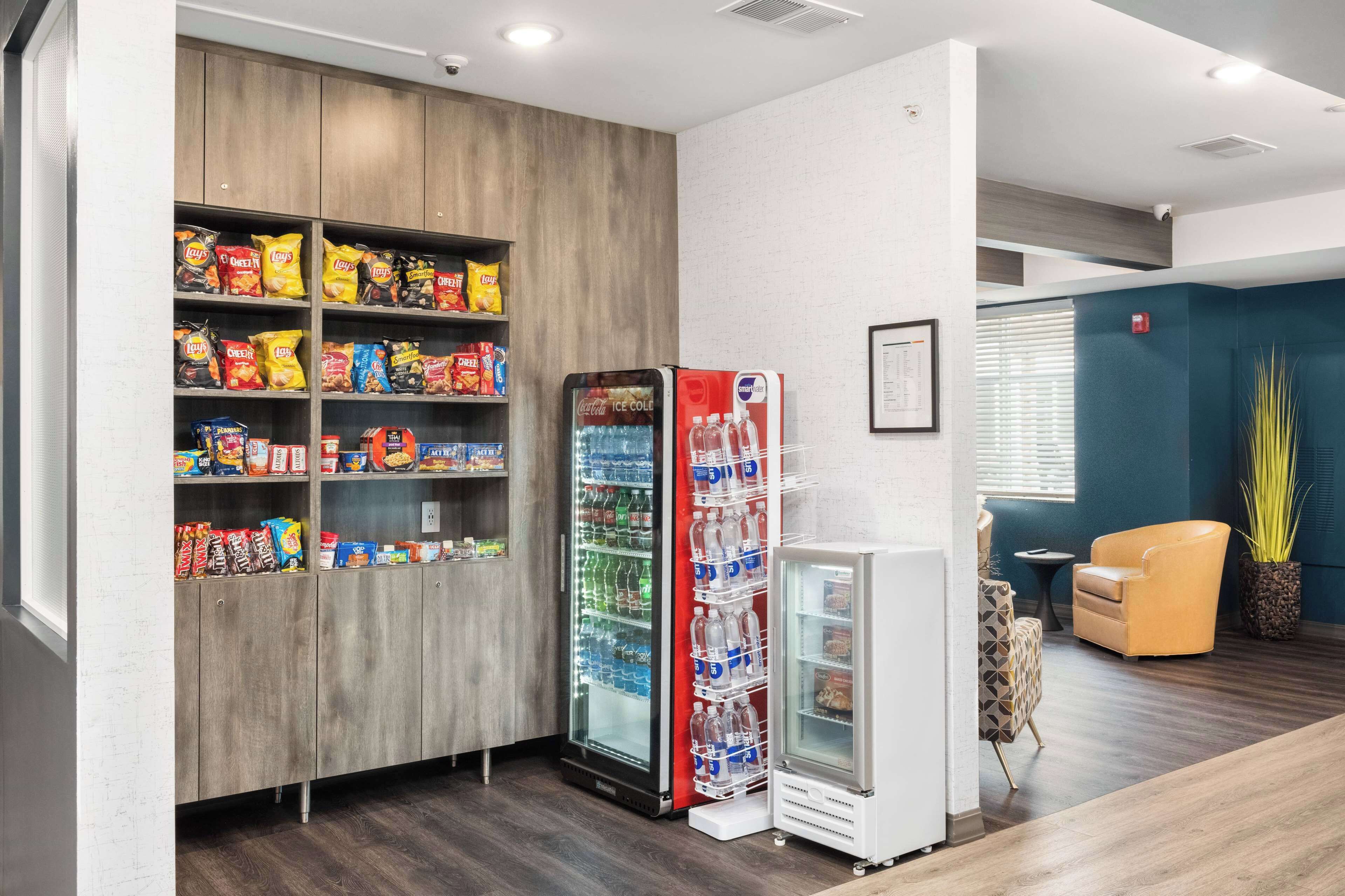 A snack bar with shelves of chips and a Coca-Cola refrigerator.
