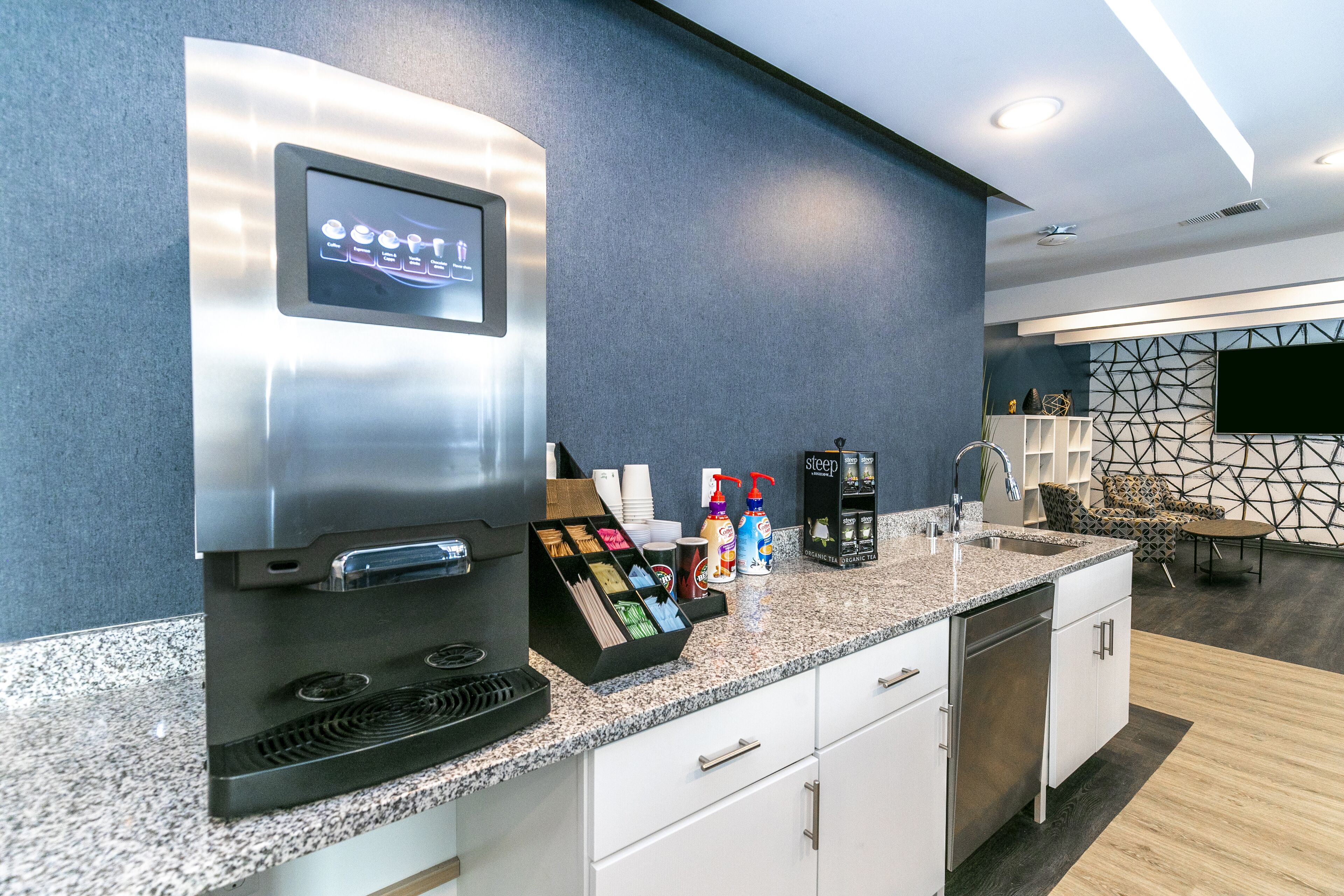 A modern kitchen with a built-in coffee machine, a beverage dispenser, and a countertop with various items.