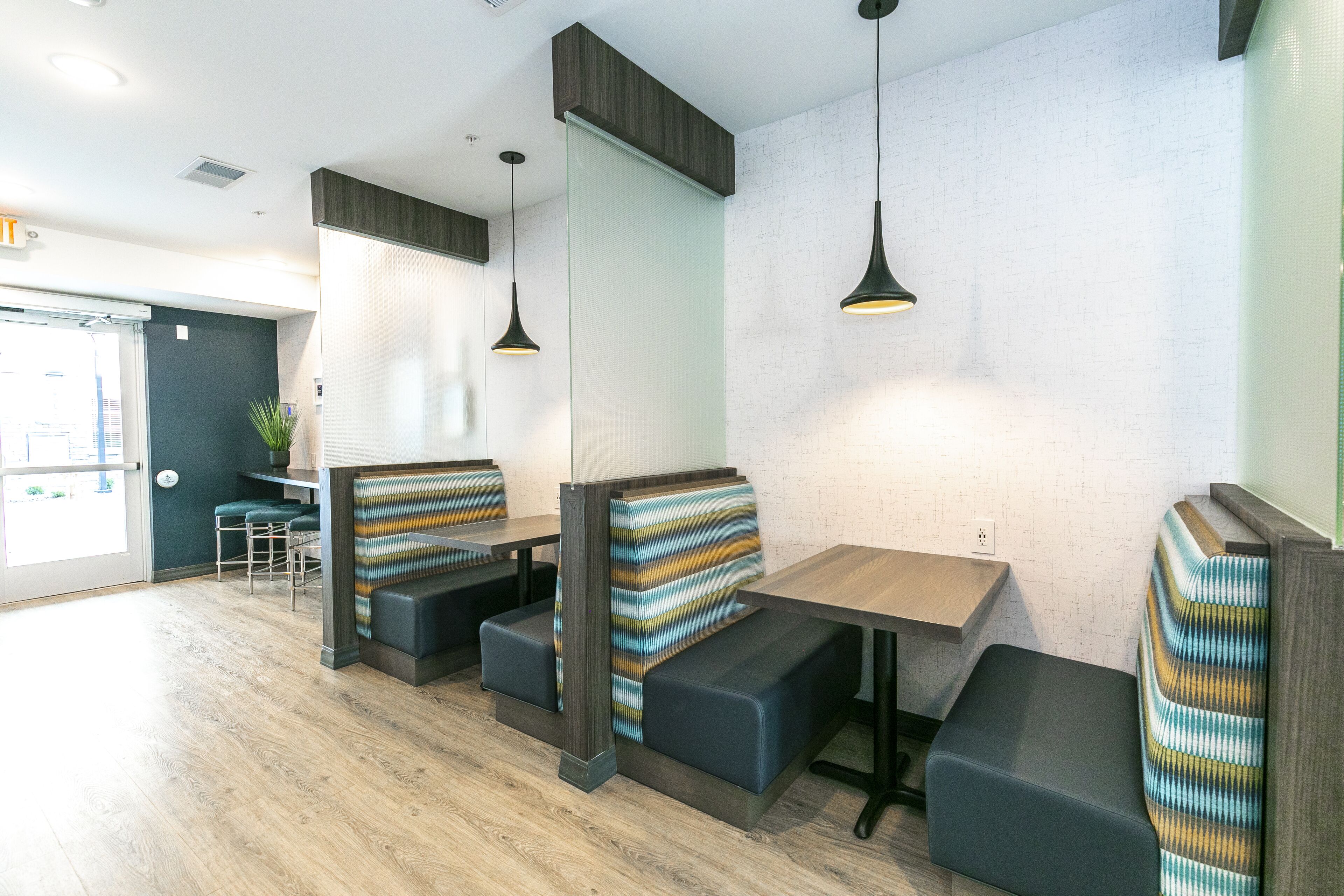 A modern restaurant with booth seating, wooden tables, and pendant lighting.