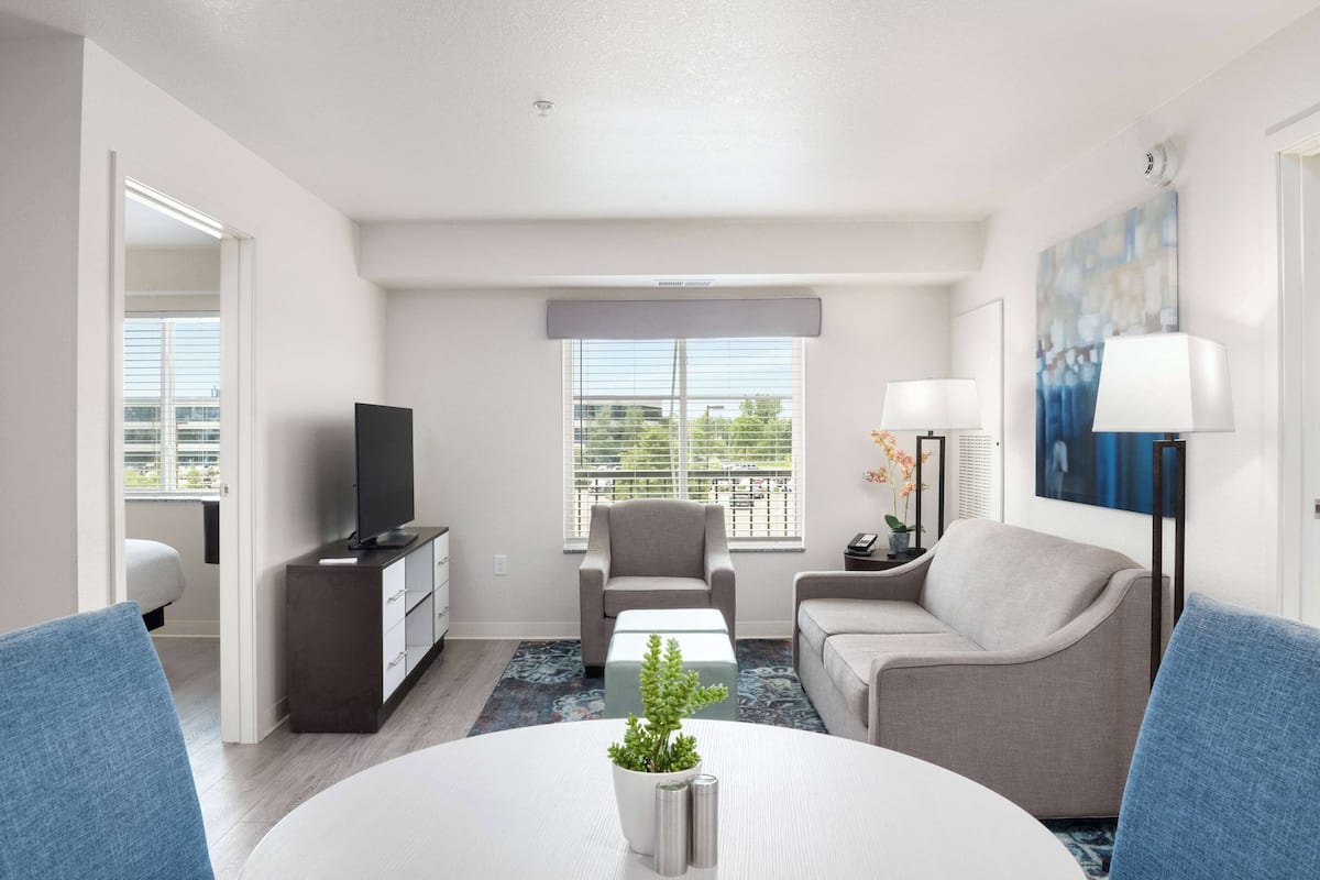 A modern living room with a flat-screen TV, two sofas, a coffee table, and a dining table.