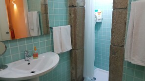 Bathroom features a sink, mirror, and shower area with a curtain and toiletries.