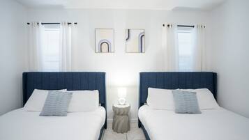 Een tweepersoonskamer met twee bedden, een nachtkastje met lamp en kunst aan de muur.