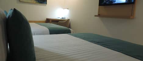A hotel room with two beds, a desk, a chair, a television, and a painting on the wall.