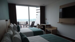 A hotel room with two beds, a desk, a chair, and a TV.