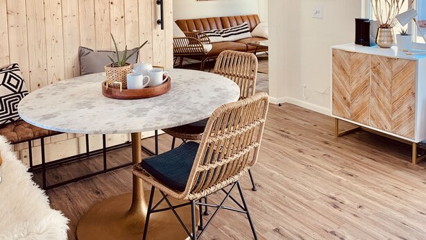 A modern living room with a round marble table, wicker chairs, a sofa, and a wooden cabinet. - Comfy Cottage With Writer Cabin and Book Nook. Pet-Friendly Fully Fenced Yard (Joshua Tree)