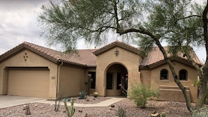 A two-story house with a garage, arched entrance, and a landscaped garden with cacti.