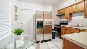 Una cocina moderna con electrodomésticos de acero inoxidable, armarios de madera y una mesa de comedor de vidrio.