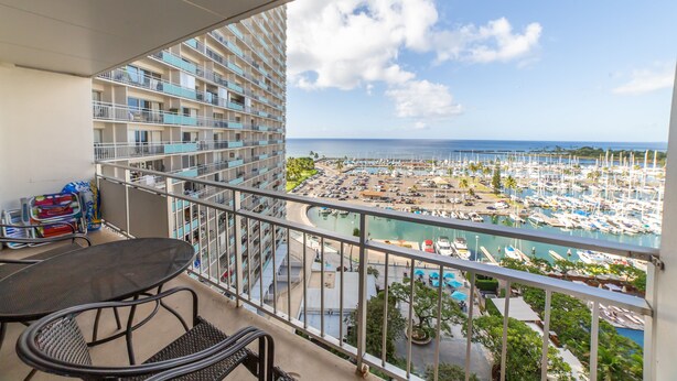 A balcony with a view of a marina, a pool, and a building with multiple balconies. - Luxury Ocean Marina View Studio World Famous Ilikai NO RESORT FEES! FREE WIFI (Honolulu)
