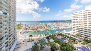 A marina with numerous boats docked, surrounded by hotel buildings with balconies overlooking the water. - Luxury Ocean Marina View Studio World Famous Ilikai NO RESORT FEES! FREE WIFI (Honolulu)