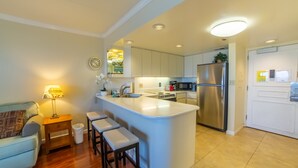 A modern kitchen with a central island, stainless steel appliances, and a dining area with a sofa and bar stools. - Luxury Ocean Marina View Studio World Famous Ilikai NO RESORT FEES! FREE WIFI (Honolulu)