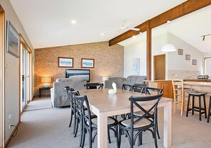 A modern interior with a dining area, a sofa, a TV, and a kitchen area. - The Waterfront - Close to shops, club, boat ramp! (Gwandalan)