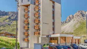 A modern multi-story hotel with balconies, a stone facade, and a mountainous backdrop. - Le Borsat (Val Claret) by Interhome (Tignes)