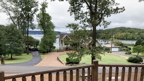 Ett bostadsområde med en träveranda, en uppfart som leder fram till ett hus och utsikt över en sjö och kullar i bakgrunden.