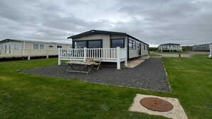 A mobile home with a deck and a small outdoor seating area.