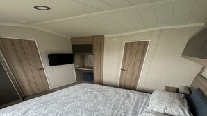 A bedroom with a bed, a TV mounted on the wall, and a closet with a mirror.